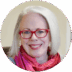 Portrait of a smiling older woman with white hair, wearing red glasses and a vibrant pink and purple scarf. She appears friendly and approachable, ready for professional residencies.