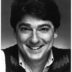 Black and white portrait of a smiling man with tousled hair, wearing a sweater vest over a collared shirt. He has a friendly and approachable expression, ideal for promotional materials in tuition management.