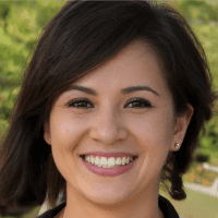 Close-up portrait of a smiling woman with shoulder-length dark hair, wearing subtle makeup and a neutral background. Her cheerful expression conveys positivity.