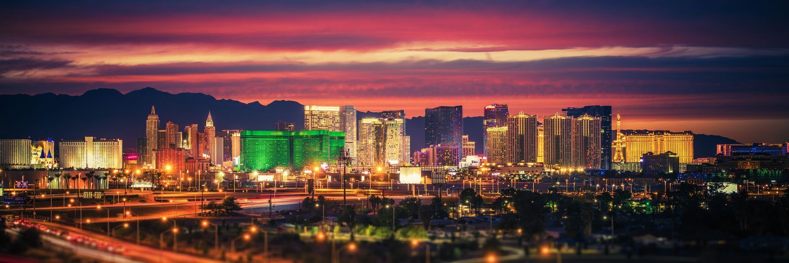 Panoramic view of las vegas skyline at twilight with illuminated hotels and casinos under a vibrant red sky.
