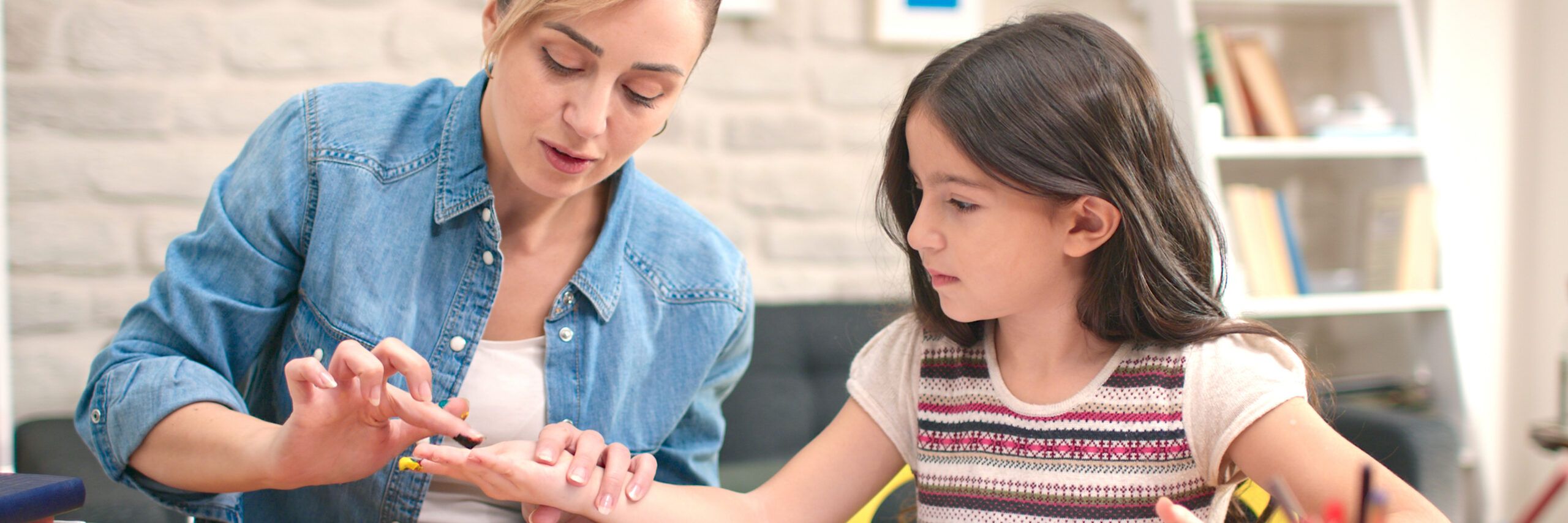 At the desk, the girl and her mother paint with their fingers. Happy family. The concept of having a good time with their children.