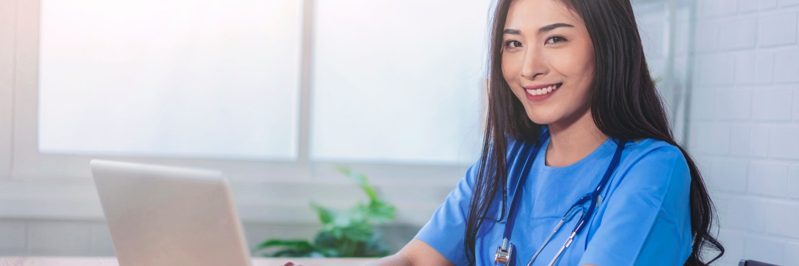 Beautiful Asian doctor working in hospital office using computer laptop tablet pad device technology working research diagnosis patient information analysis happy smiling cheerful professional uniform